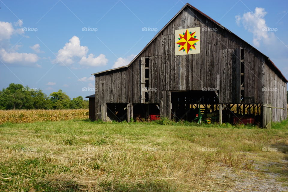 A barn with a quilt square painted on it by 5he side of a road on a late summer afternoon on a scenic route in Kentucky.