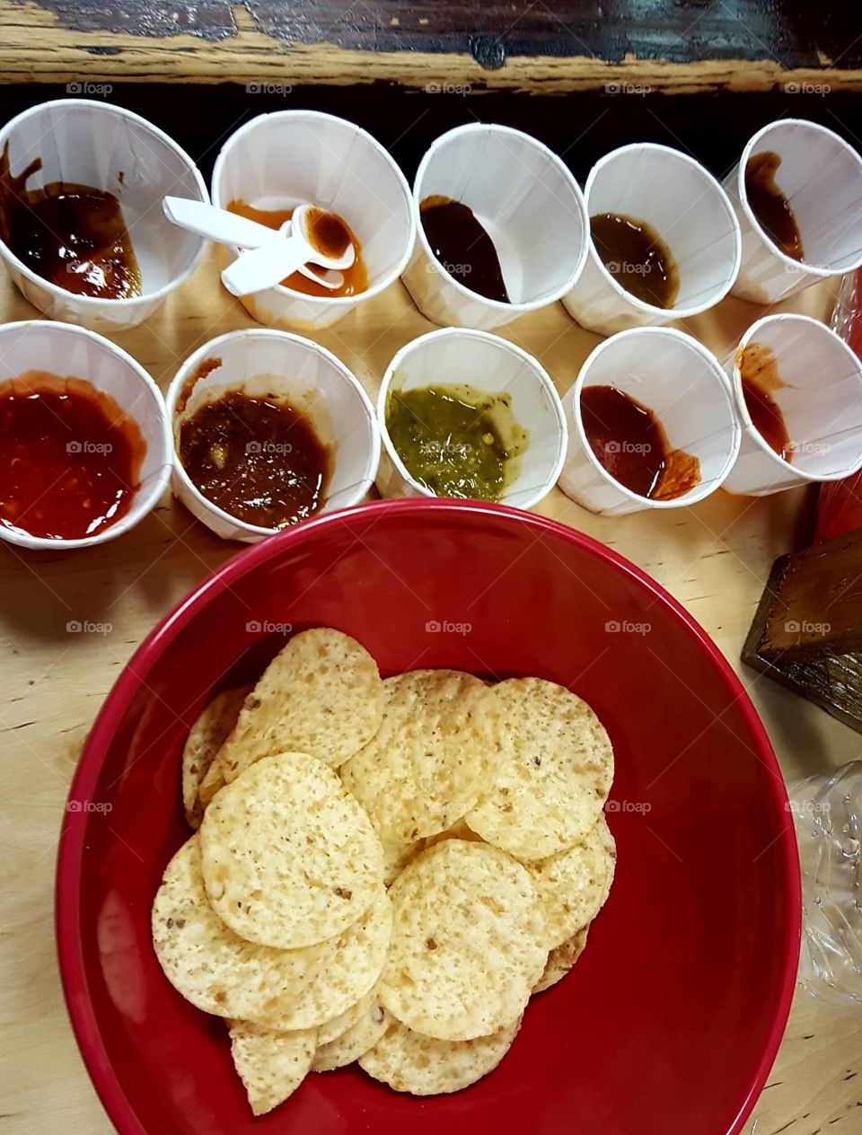 Tortilla chips in a colorful bowl with a sampling of different hot sauces