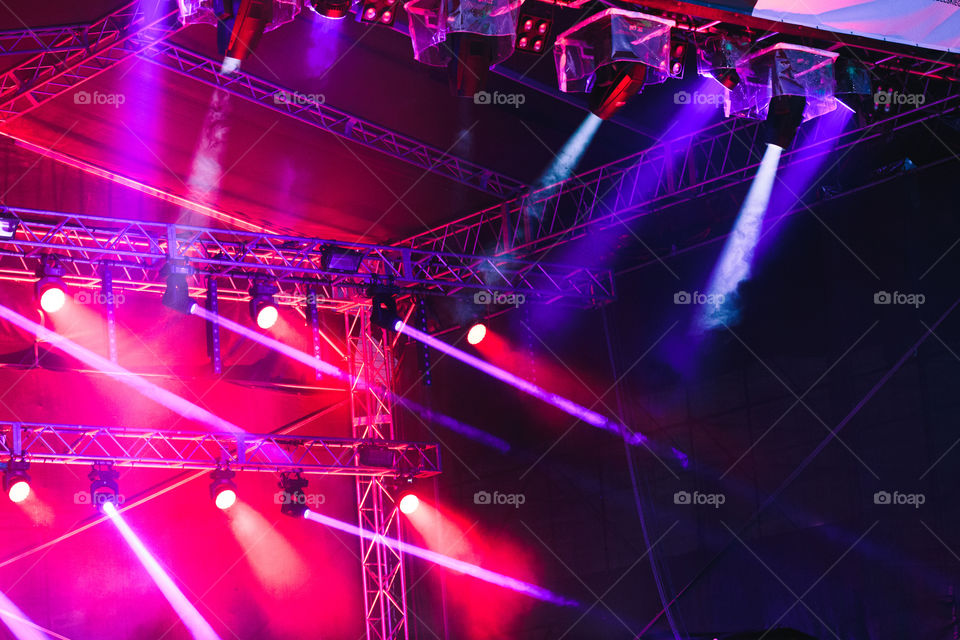 Spotlights, red and blue beams of lights above stage during concert event festival