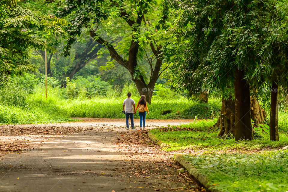 Portrait of two joyful young loving Couple walking in a green autumn park on a romantic summer day. Pre-wedding marriage engagement concept. Togetherness composition. Botanical garden, Kolkata, India