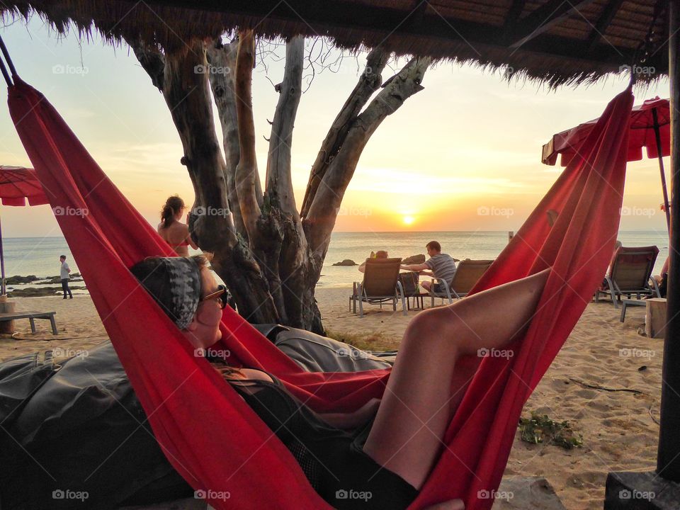 Woman on hammock at beach during sunset