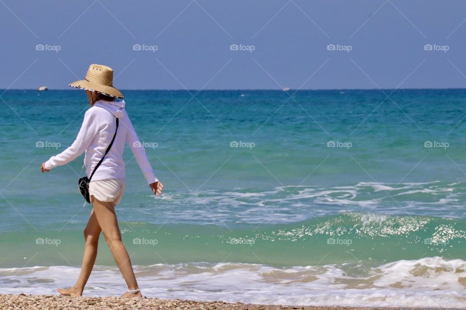Woman walking on the beach with turquoise water