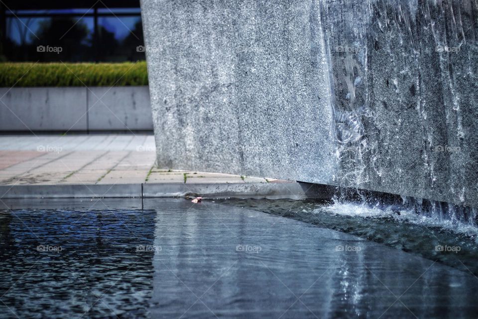 Water flows from a concrete fountain on the wall into a basin