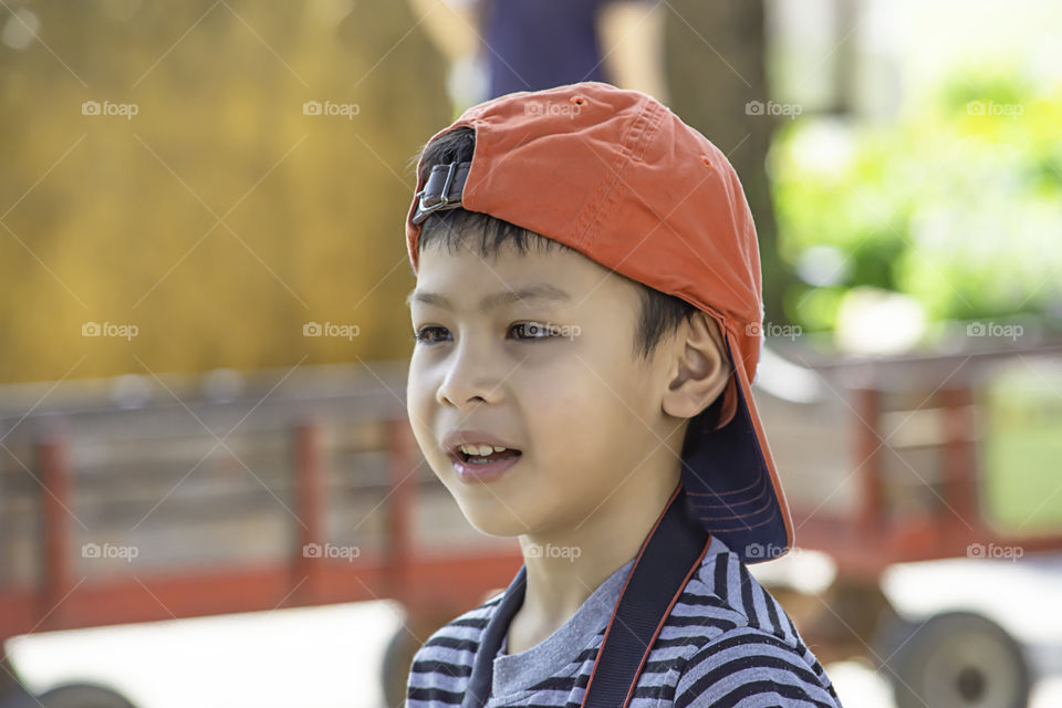 Portrait of Asian boy wearing a hat and smiled happily in park.