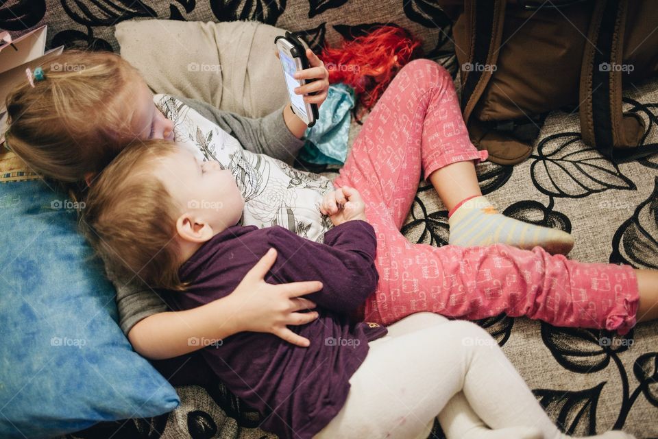 Two little kids watching video on smart phone