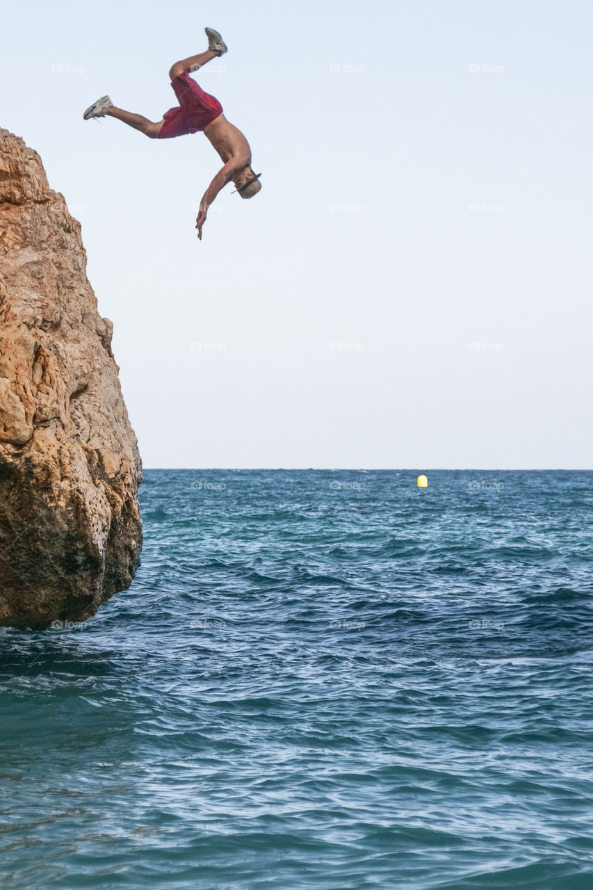 A man in a hat is jumping into the sea. Spain 
