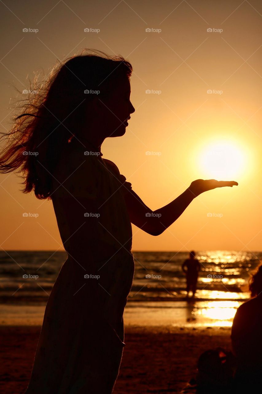 Silhouette of a girl holding the sun 