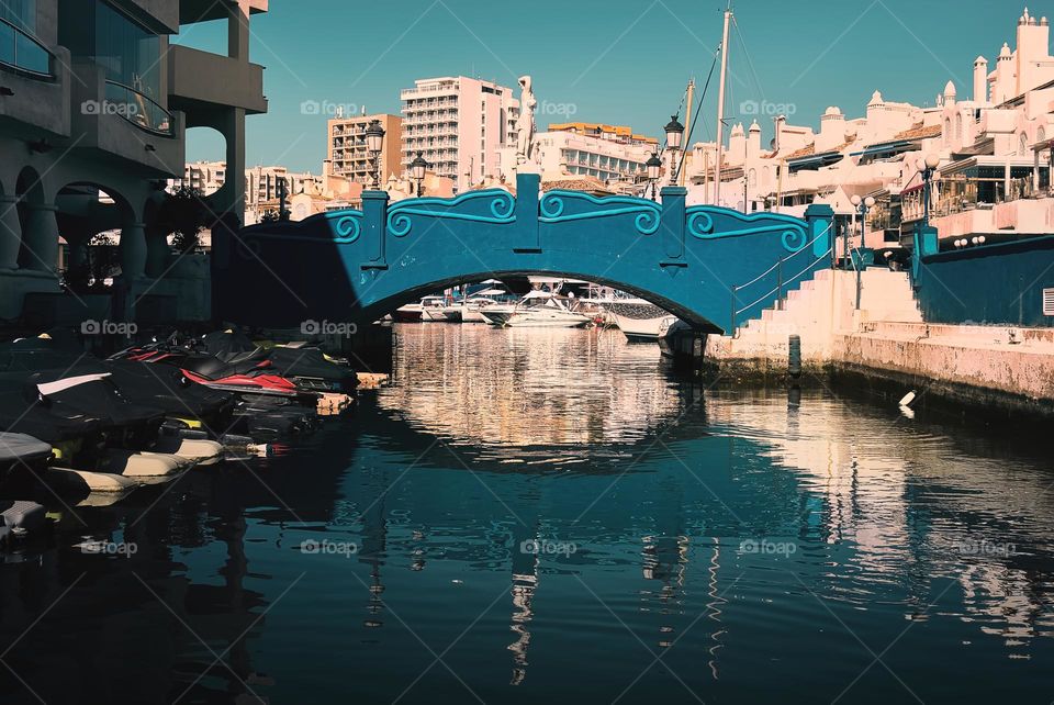 Blue bridge over ocean under clear blue skies at Banalmadena marina, Spain