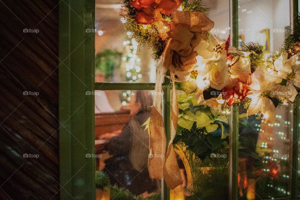 An elderly playing piano seen from a decorated window 