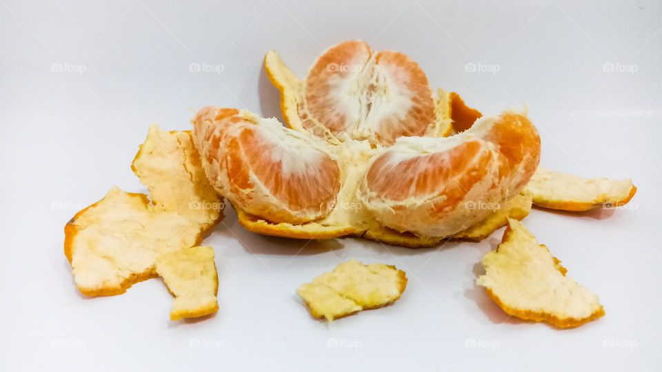 Peeled and split orange fruit on isolated white background in eye level view