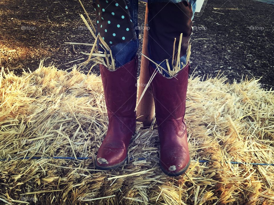 Cowboy, cowgirl boots on a scarecrow on a haystack at the pumpkin patch - enjoying the autumn season 