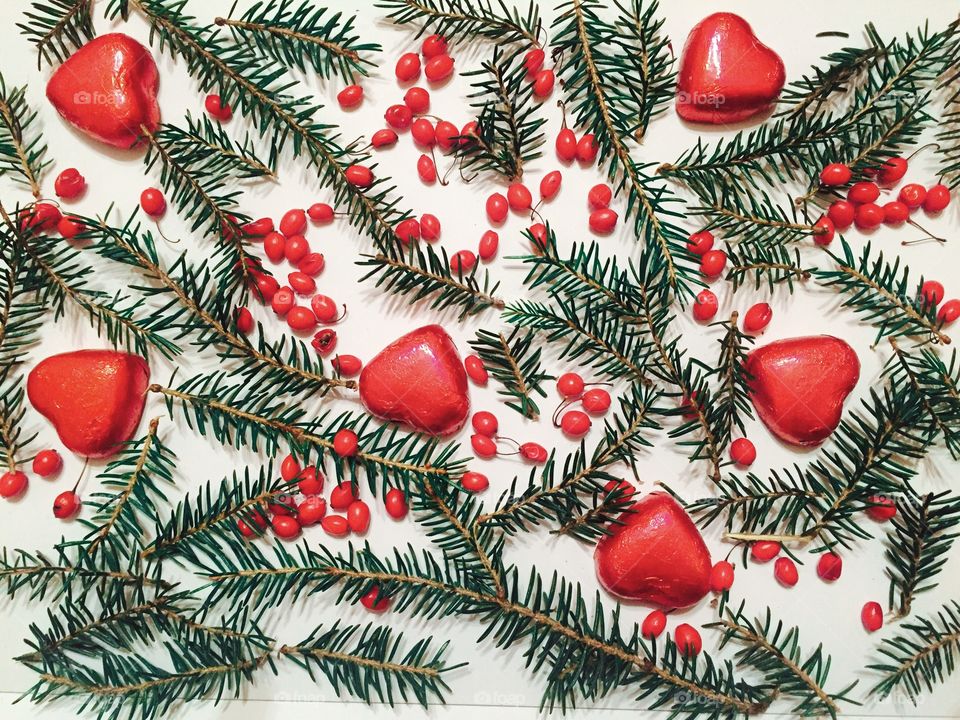 Red chocolate hearts with pine cone tree branches on white background 