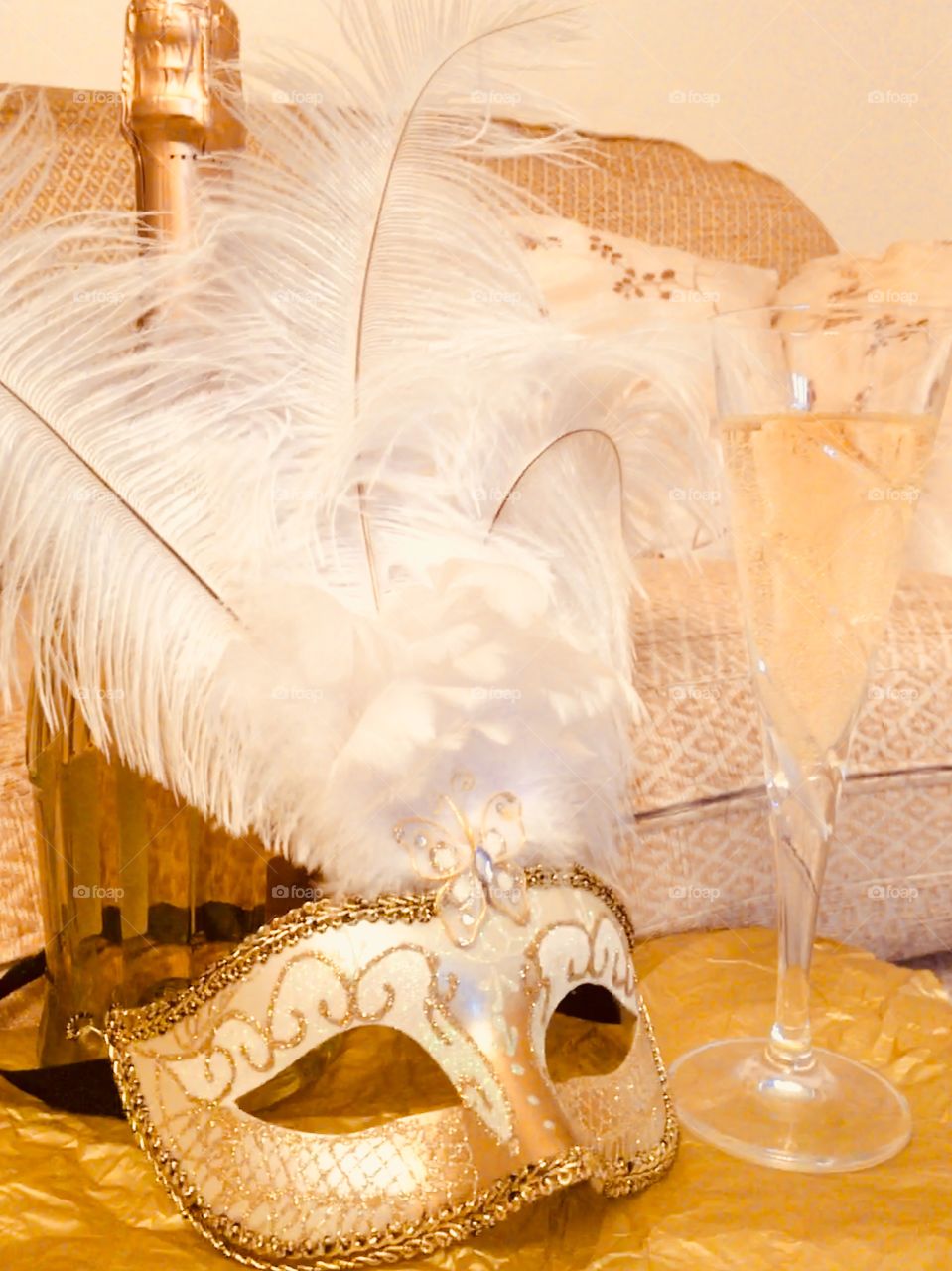 Gold Venetian masquerade mask with a bottle of Moscato and a glass of white grape juice 