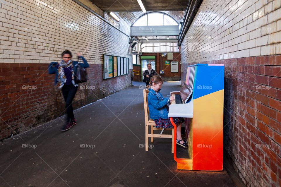 Little girl playing piano in subway tunnel.
