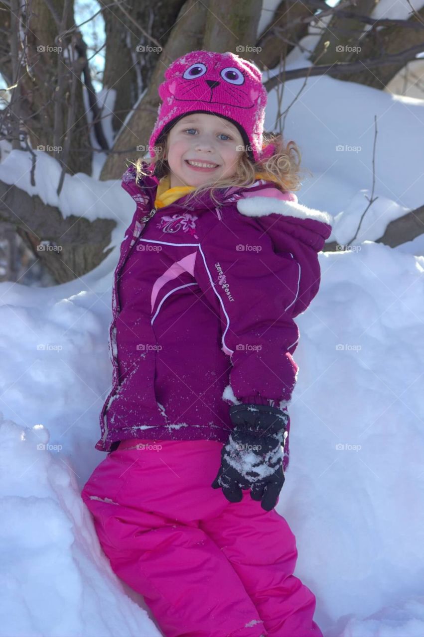 And adorable little five-year-old girl climbing in a snowbank in her winter gear. 