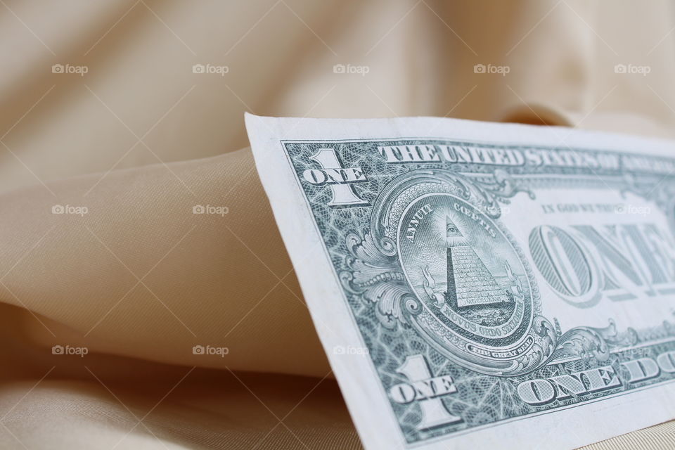 Back of a one dollar bill on a gold textile material close-up