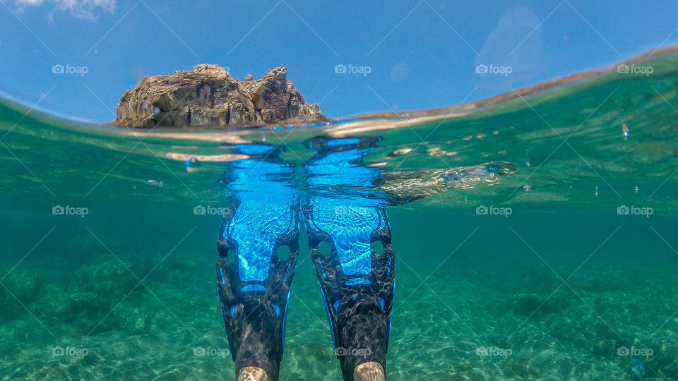Over and under water of snorkel flippers in Carribean waters