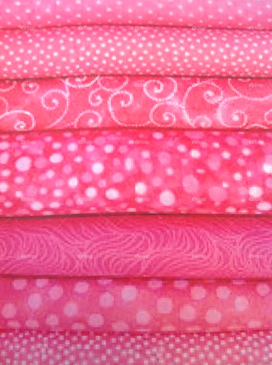 Different pink colored fabrics stacked up together.