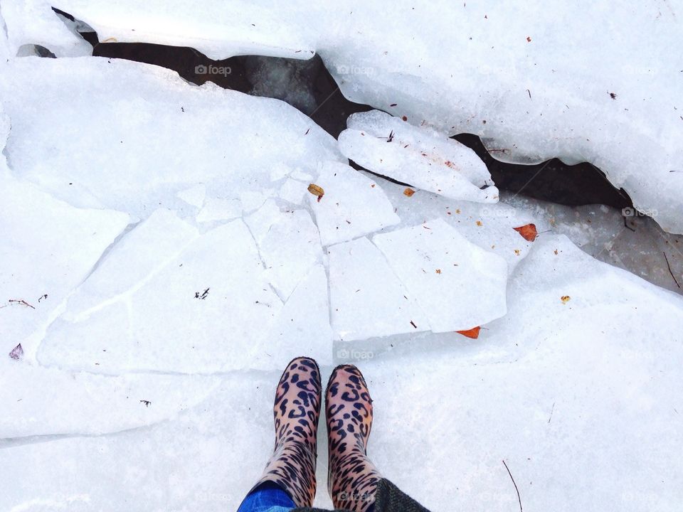 Feet view of boots standing on the white frozen river. 