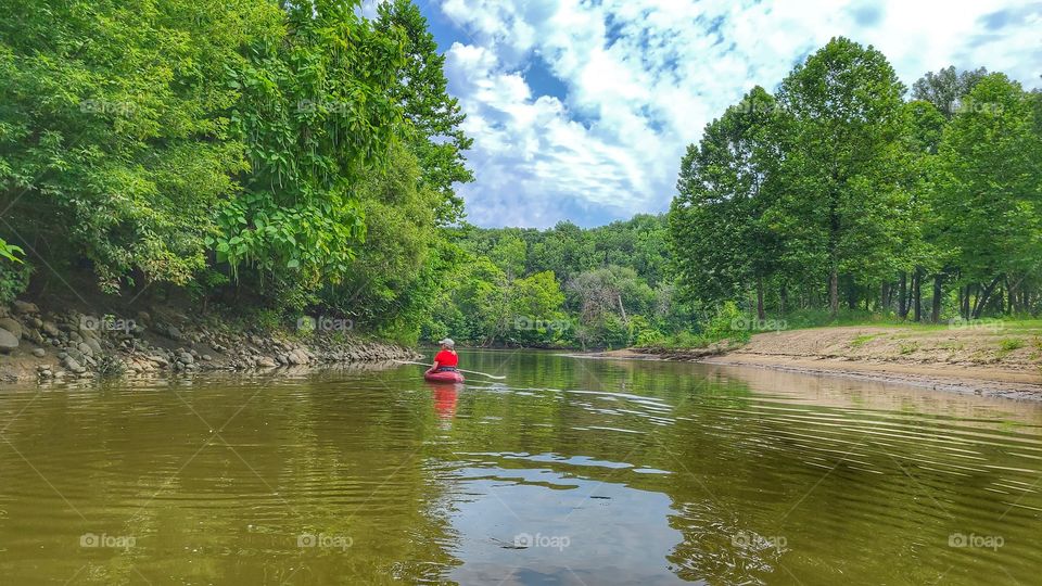 woman kayaks river in summer