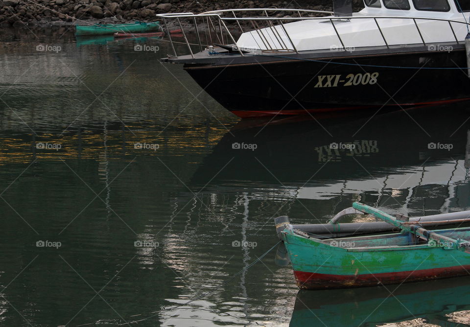 A comparationable two of boot. Traditional one , and modern boot for parking sea at the side of harbour.