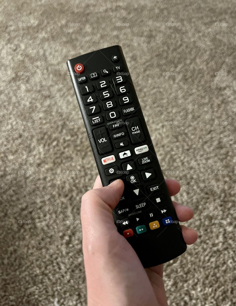 Tv remote using it on the television to change the channel.  Holding the remote in the hand.  It has a power button, volume control, colored buttons for easy use