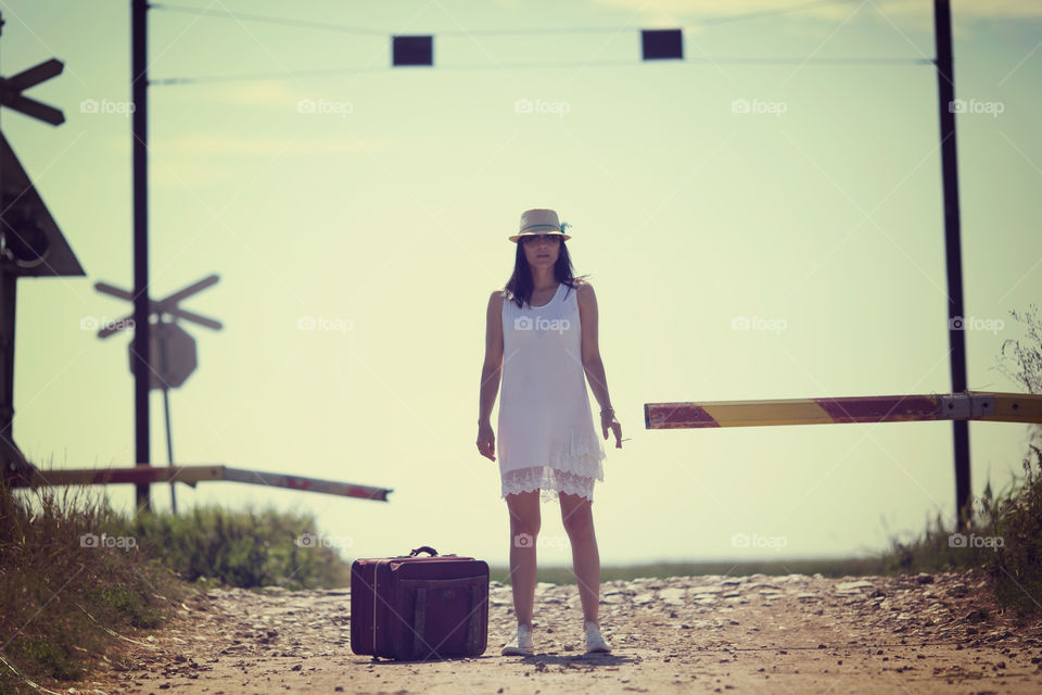 Woman in white dress standing with suitcase