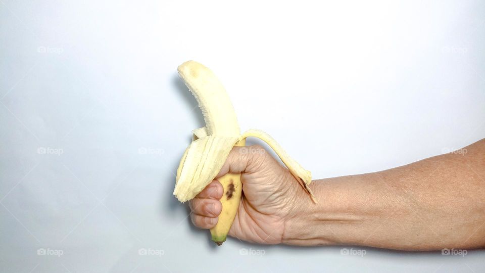 Hand is holding an open banana in eye level view