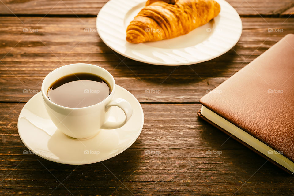 Coffee and croissant on wooden table