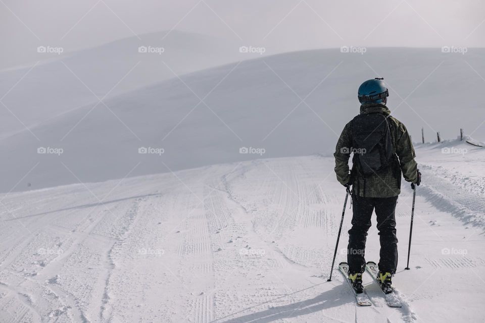 Young man admiring the winter landscape, while being on a skiing vacation, in a mountain resort from Romania.