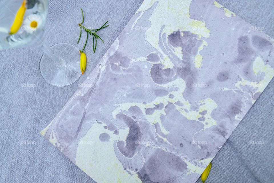 Marble paper with a glass and yellow flowers