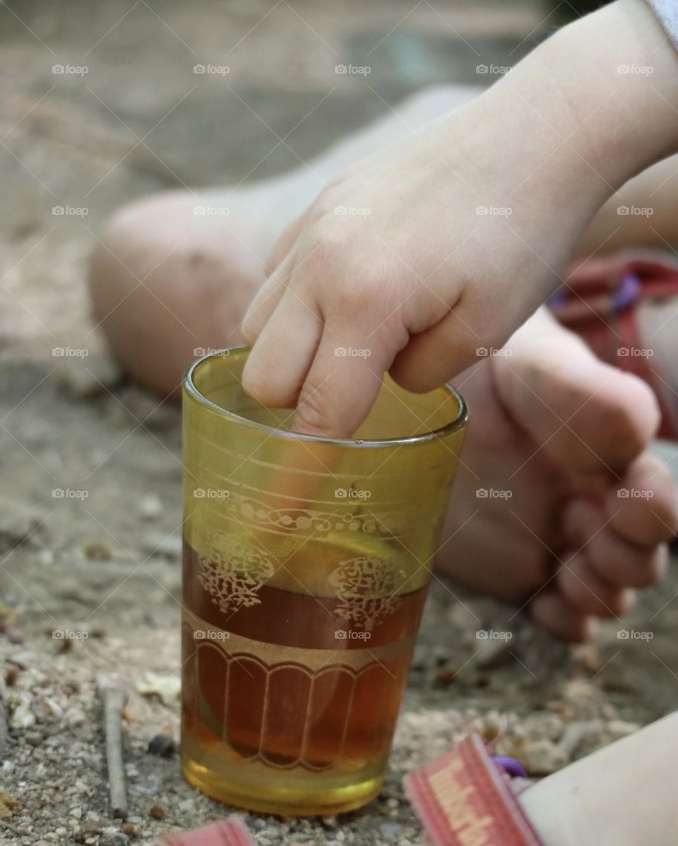 Finger into yellow tea glass 