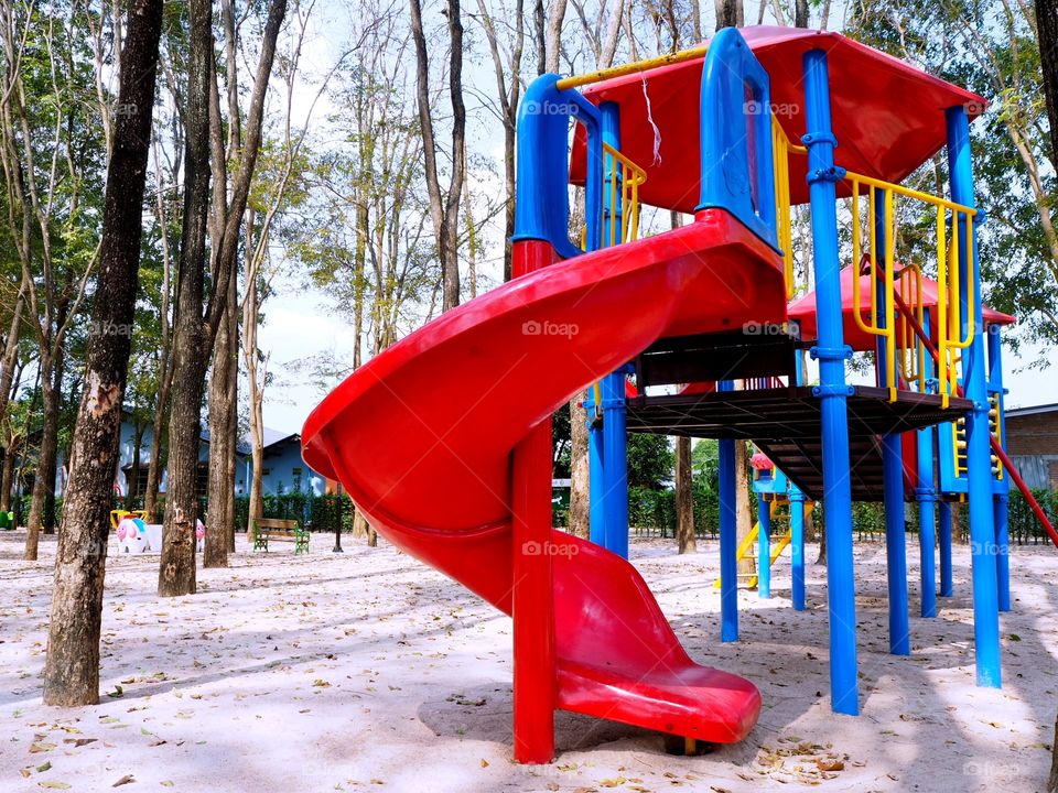An empty slide yet colorful inside a public playground or park.