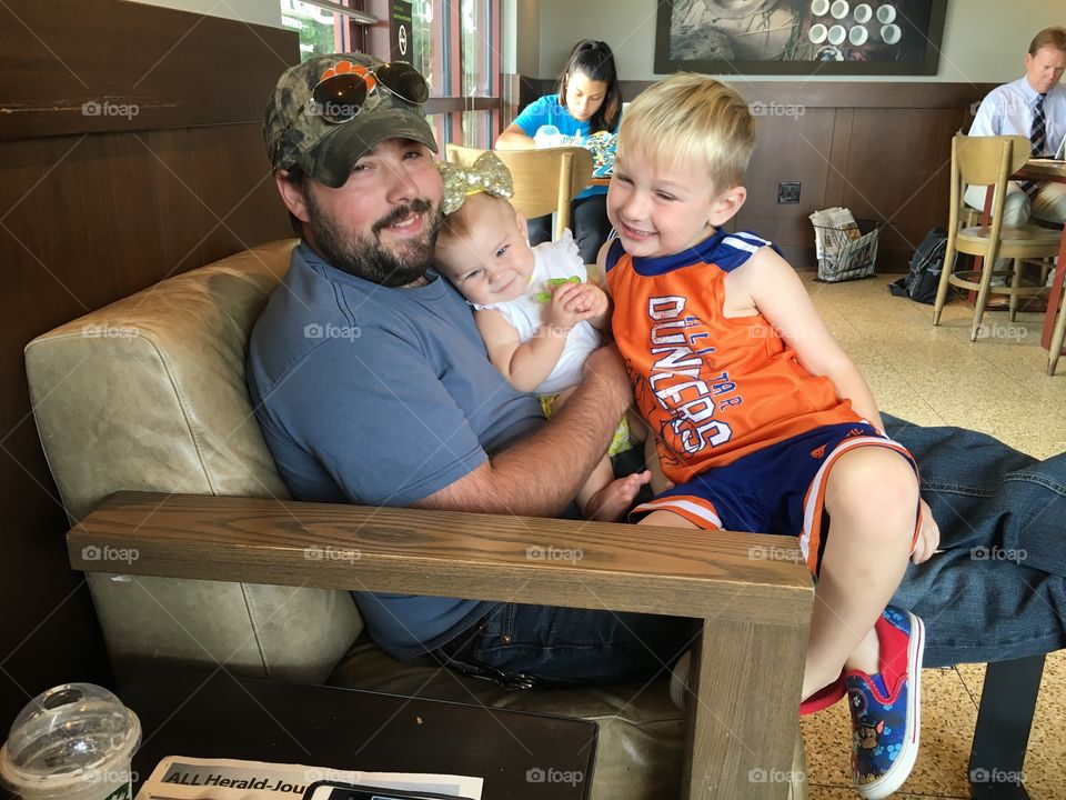 Happy father sitting in restaurant with his daughter and son