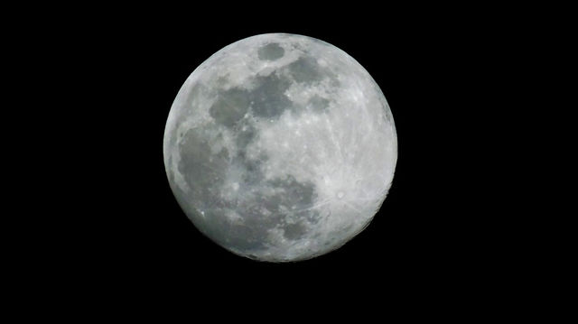 Close-up of full moon at night against blackness of outer space with craters