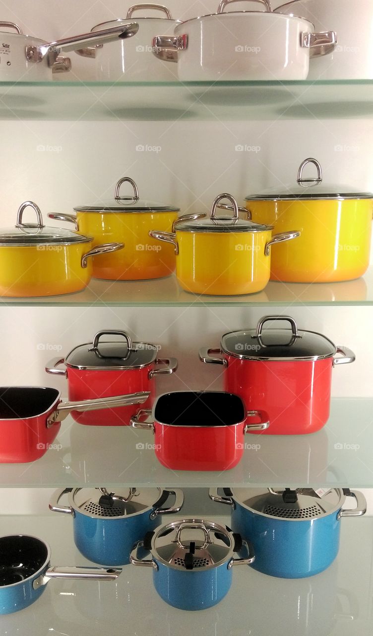 Different coloured pots standing on glass shelves