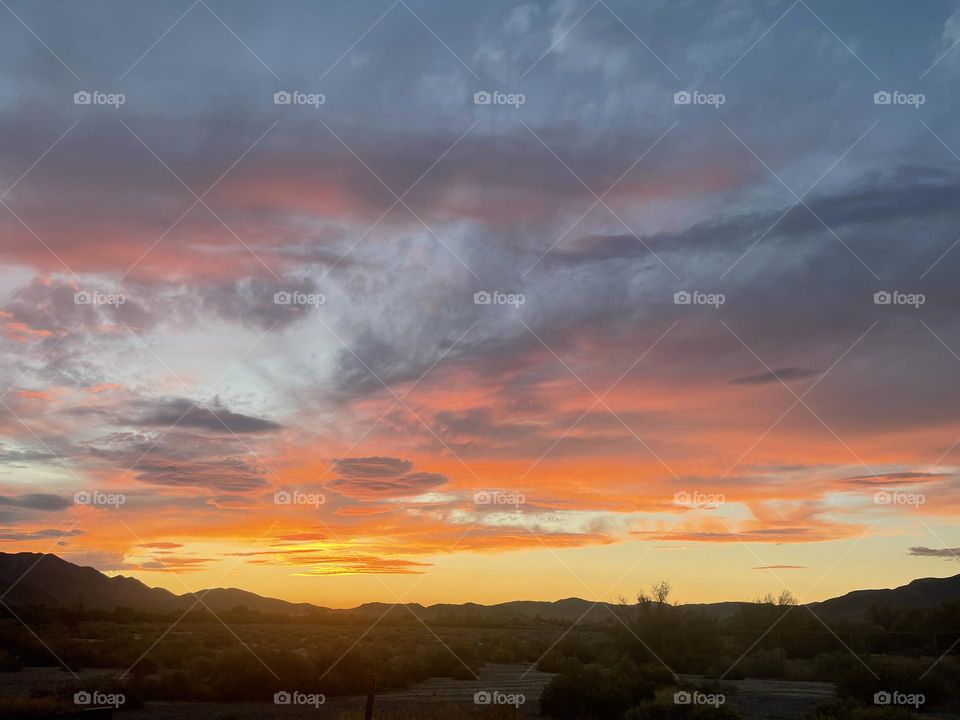 A yellow and pink sunset with mountains below.