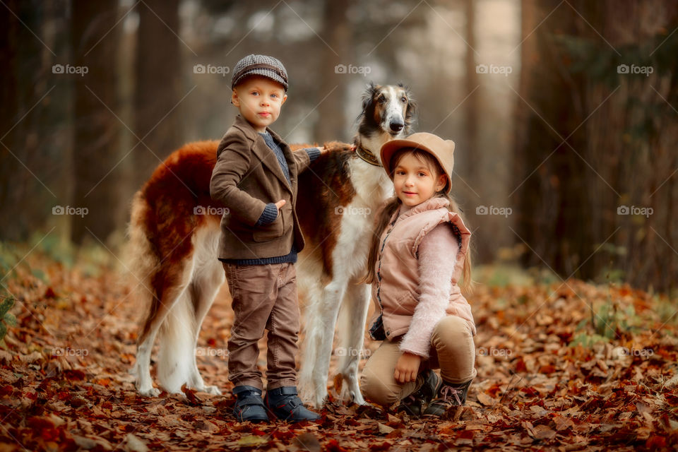 Children with russian borzoi dog in an autumn park 