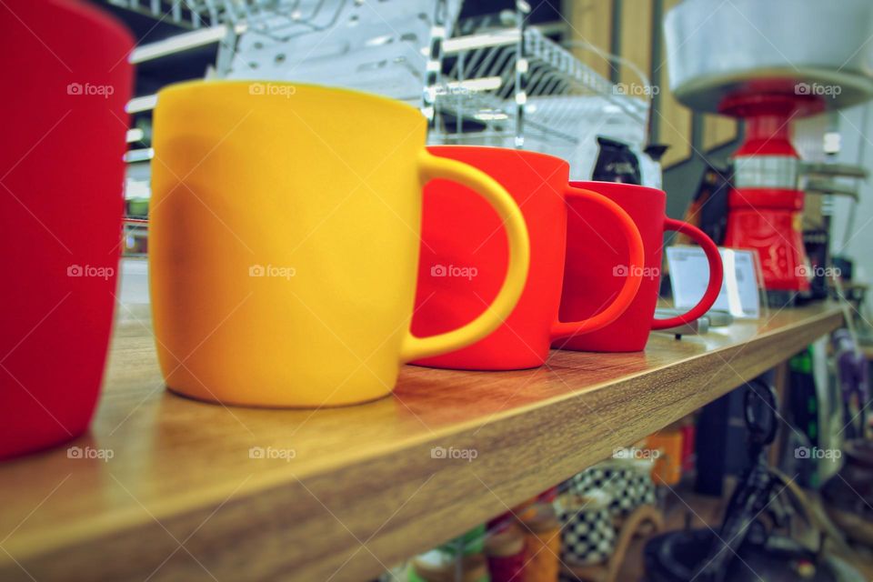 several mugs on the bar. yellow, red and orange mugs