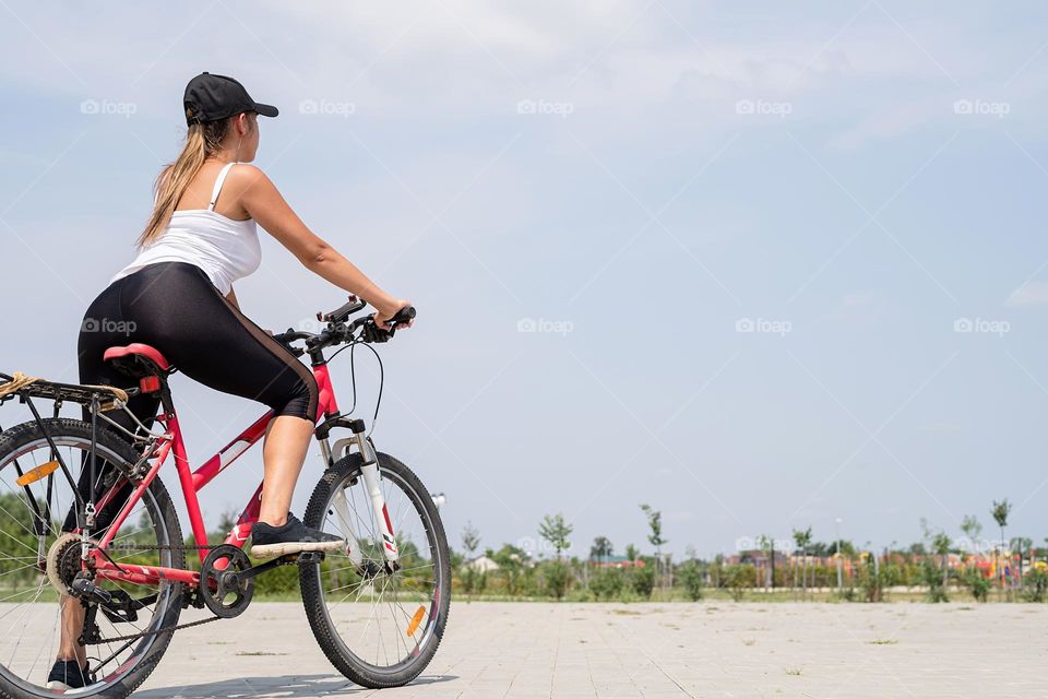 woman in sports clothes and cap riding her bicycle