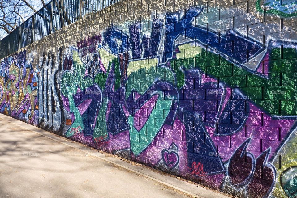 Colorful abstract graffiti and lettering on the brick wall by the path in Krejcarek park in Prague, Zizkov.