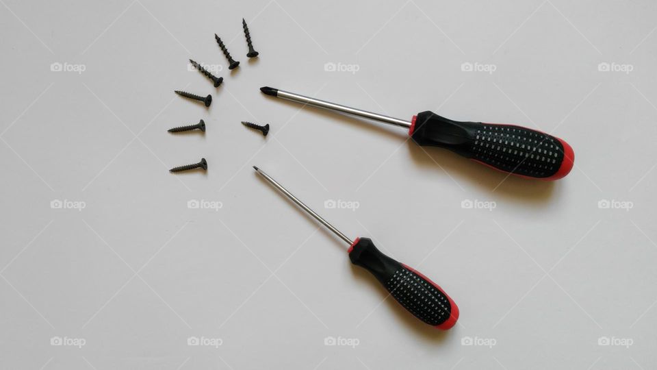 two screwdrivers and screws on a white background