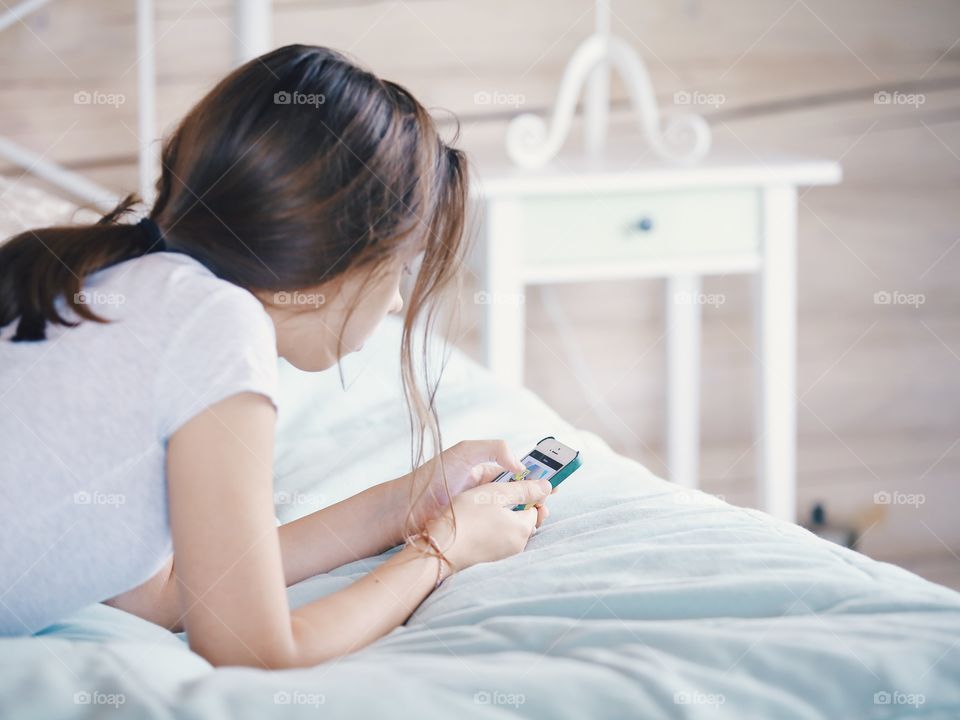 Girl lying on the bed and using mobile