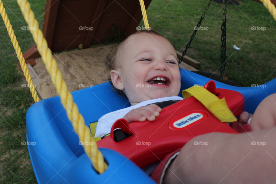 Baby boy smiling in a swing.
