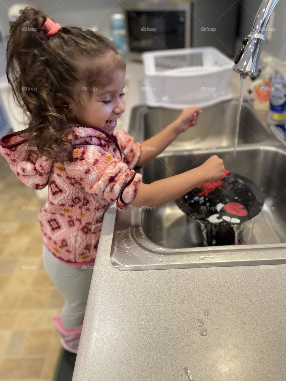 Toddler having fun at the kitchen sink, washing up toys in the sink, toddler does the dishes, water time fun 