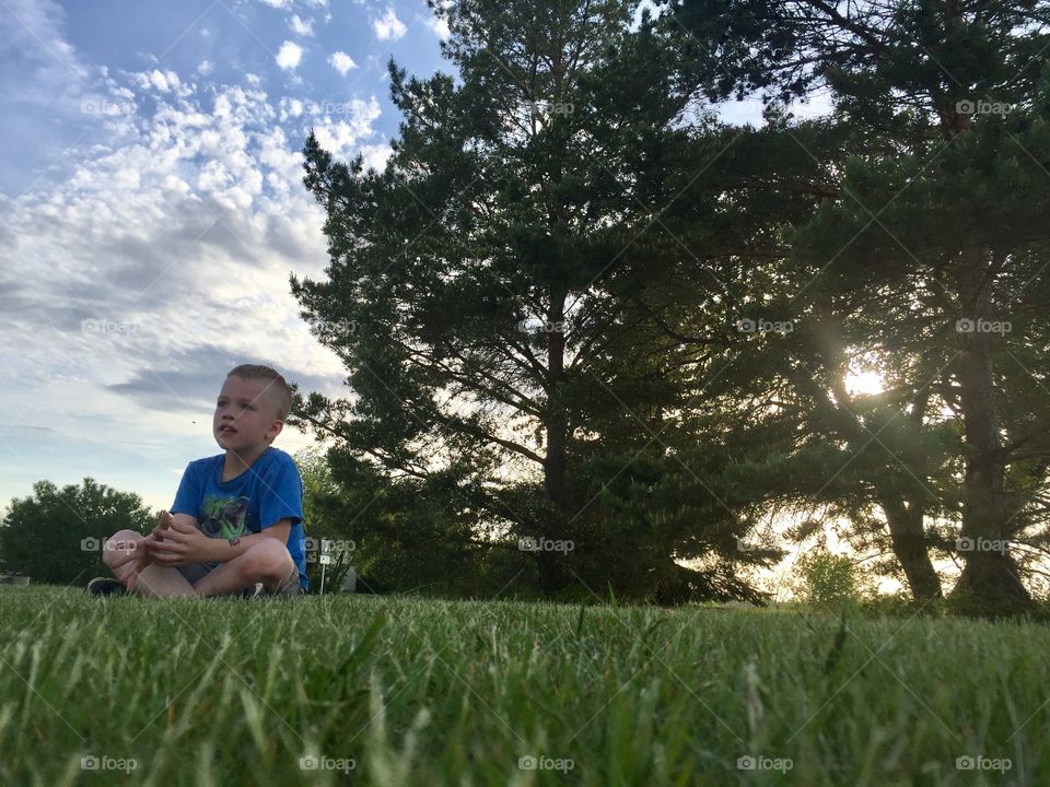 Boy sitting on green grass in he park