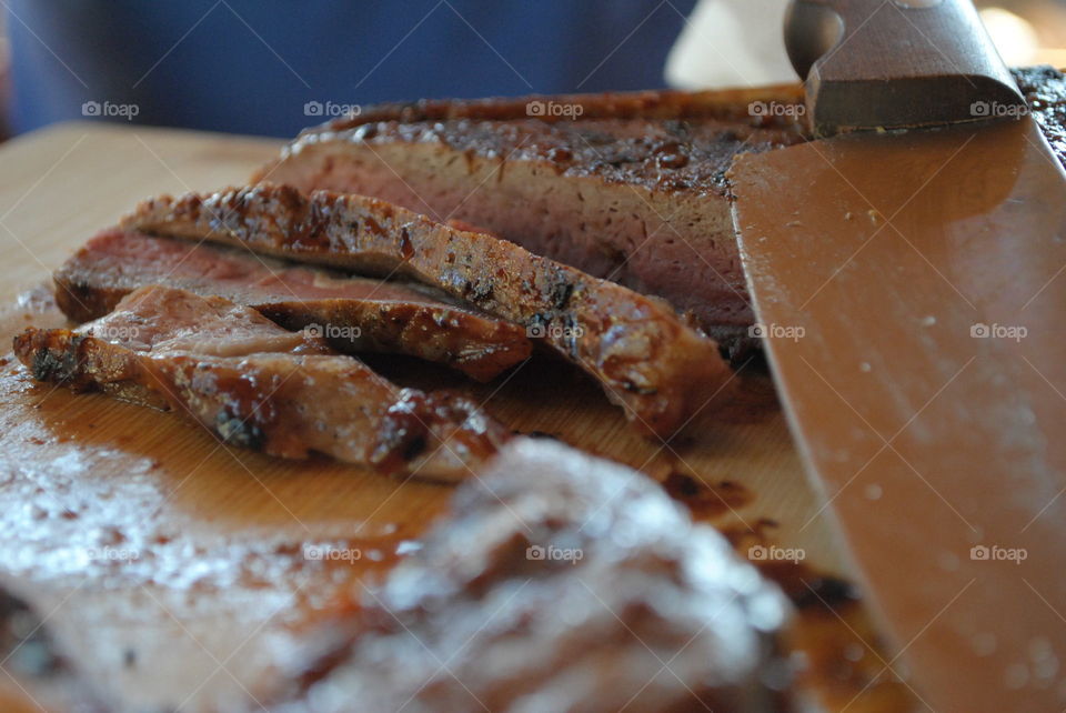 cutted steaks on wooden plate with knife