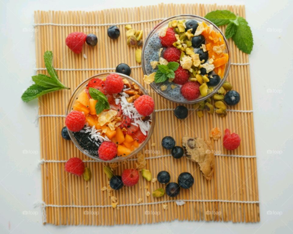 Healthy Fresh Fruit Smoothie Bowl - creamy raspberry smoothie topped with peach, seeds, dry coconuts,  nuts, blueberry and strawberry