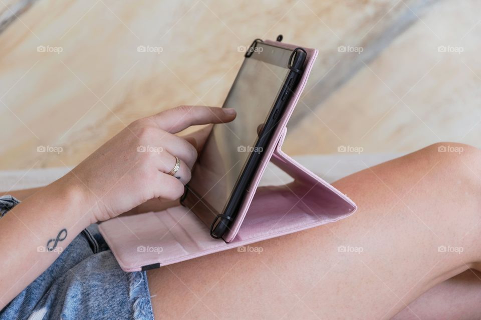 Hands of woman using a tablet computer in the sofa at home