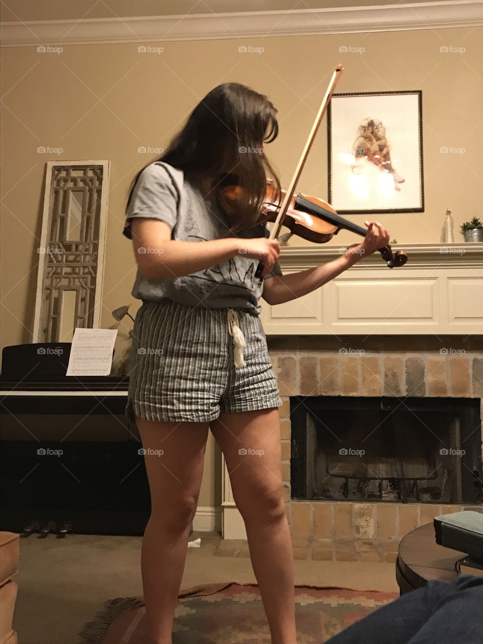 A passionate musician practicing at home. Comfortable clothes, cozy living room, fireplace, and a beautiful violin. 